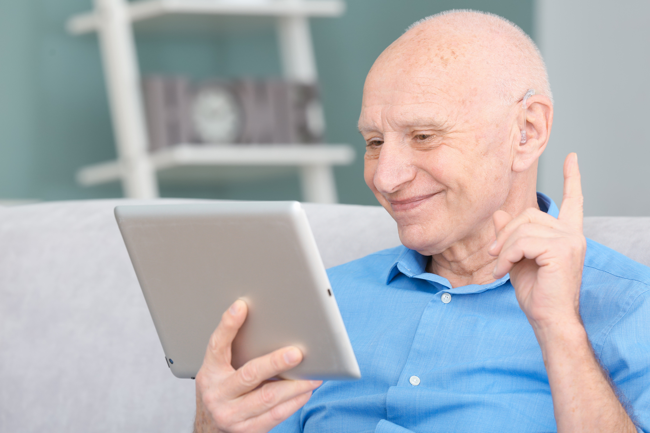 Senior Man with Hearing Aid Using Tablet Computer