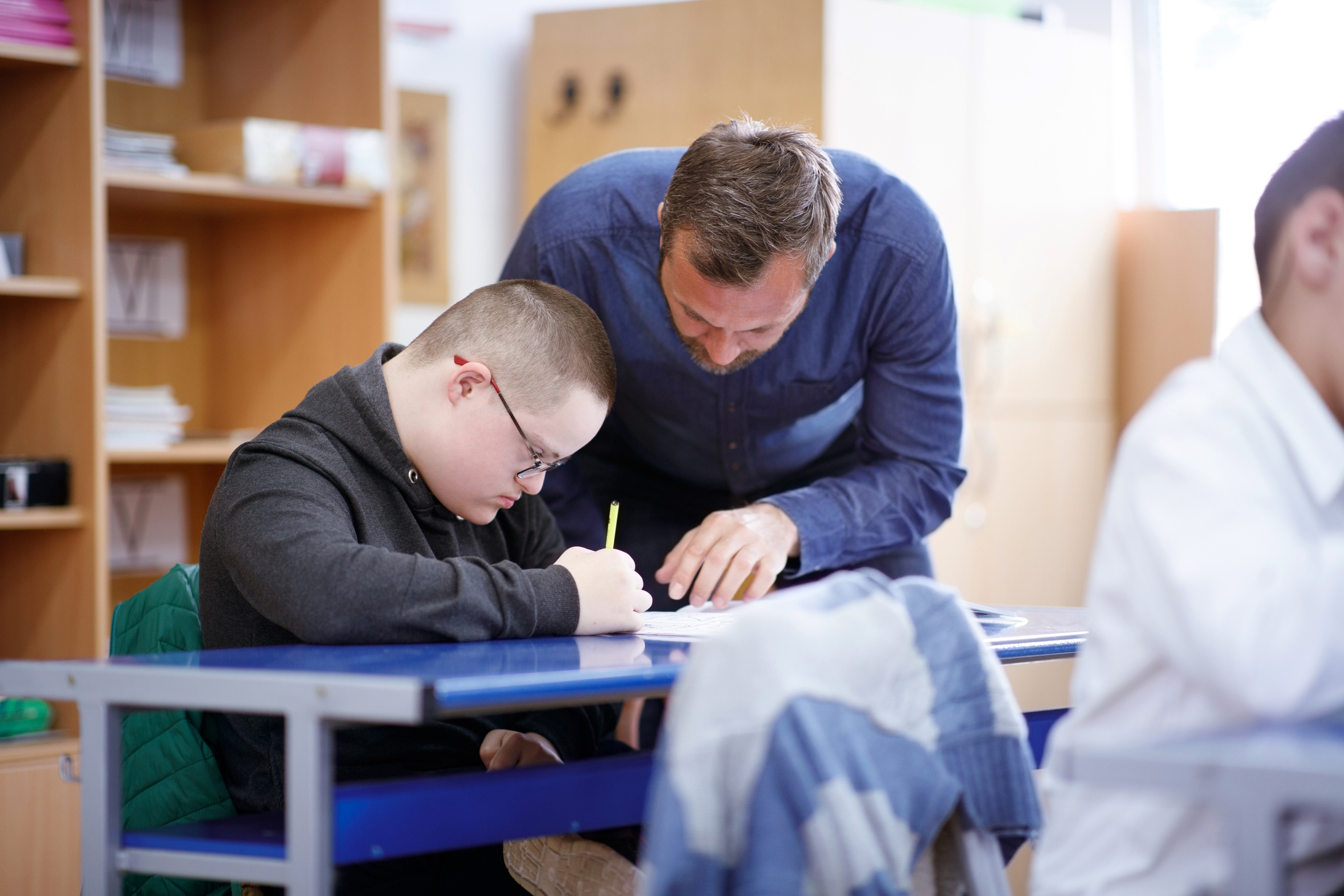 Teacher helping intellectual disabled boy on his drawing skills